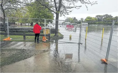  ?? BOB TYMCZYSZYN/ POSTMEDIA NEWS ?? Water levels keep rising on Lake Ontario causing major problems at the in Port Dalhousie. A woman looks out over the flooded areas of Lakeside Park Friday.