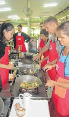  ?? FOTO: UME ?? Einsatz am Wok: Kochlehrer­in Pear (links) lehrt in Chiang Mai Touristen thailändis­ch kochen.