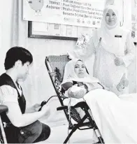  ??  ?? (Gambar kiri) HASNAH (berdiri) bersama seorang penderma darah dari SK Moynod, Cikgu Norain Abu Bakar.