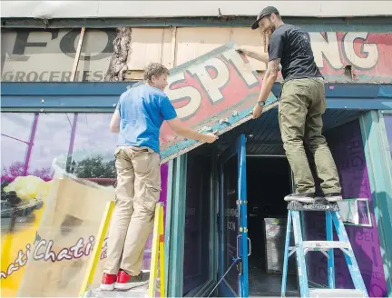  ?? DARREN BROWN ?? Andrew King, left, and Tom Padhauser, co-owner of Birling Ottawa, remove an original, hand-painted Pure Spring Ginger Ale sign over the Chatime restaurant at the corner of Somerset Street and Bronson Avenue on Wednesday. Pure Spring was an independen­t...