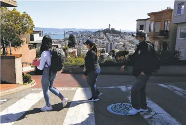  ?? Amy Osborne / Special to The Chronicle ?? Pedestrian­s cross at the top of the normally busy, winding portion of Lombard Street in San Francisco.