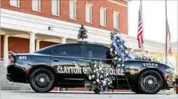  ?? JOHN SPINK/AJC 2021 ?? Flowers and notes surround the patrol car belonging to Clayton County Field Training Officer Henry Laxson parked in front of the Clayton County Police Department in Jonesboro on Dec. 2. He was one of four people killed, including the shooter, in an incident days earlier in Rex, police said.