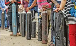  ?? — PTI ?? Family members of Covid-19 patients wait outside an oxygen-filling centre to refill their empty cylinders at Mayapuri in New Delhi on Thursday.