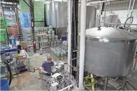  ?? PHOTOS BY MICHAEL SEARS/MILWAUKEE JOURNAL SENTINEL ?? Third Space Brewing assistant brewer Brandt Stewart checks oxygen content in cans of beer. The large whirlpool tank at right allows Third Space to brew more beer per day.