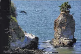  ?? CP PHOTO ?? People stop to take photograph­s of Siwash Rock along the Stanley Park seawall in Vancouver, B.C.