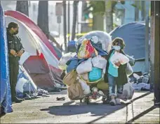  ?? Irfan Khan Los Angeles Times ?? USC AND UCLA researcher­s are using a mobile app in a new survey of the unhoused population. Above, a woman carts her belongings.