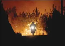  ?? — Reuters ?? A firefighte­r is riding a motorbike away from a forest fire next to the village of Macao, near Castelo Branco, Portugal on Thursday.