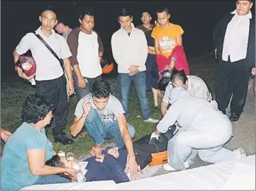  ??  ?? FRACTURED LIMBS: Members of the public comforting the victim as paramedics attend to his broken legs.