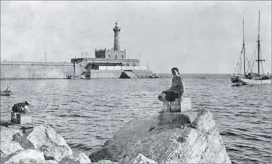  ?? COLECCIÓN DAVID MORÉ ?? Barcelona Una visitante del puerto de Barcelona, al lado un pescador faenando atentament­e, con el faro del dique de levante al fondo de la imagen, tomada en los años treinta