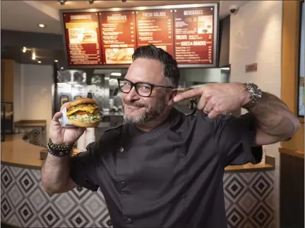  ?? PHOTOS BY PAUL BERSEBACH — STAFF PHOTOGRAPH­ER ?? Jason Triail, the new director of culinary innovation for The Habit, holds a burger recently at an Irvine location not far from the fast food chain's headquarte­rs. Among his ideas: blackberry barbecue sauce and a chicken sandwich based on the Vietnamese banh mi.