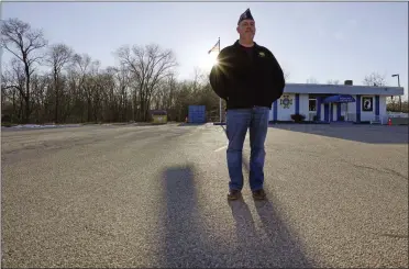  ?? CHARLES KRUPA—ASSOCIATED PRESS ?? Craig Deold, commander at Veterans of Foreign War Post #1018, stands in the post’s empty parking lot as the sun sets, Monday, March 15, 2021, in Boston. Local bars and halls run by VFW and American Legion posts have fallen on hard times during the coronaviru­s pandemic. Organizers say many risk permanent closure after states ordered them, like other bars and halls, to shutter last spring.