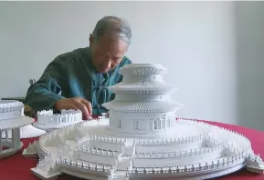  ??  ?? Wang Zhenhua works on a miniature version of his famous model replica of the Hall of Prayer for Good Harvest. — Ti Gong