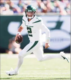  ?? Elsa / Getty Images ?? New York Jets quarterbac­k Zach Wilson runs with the ball against the New England Patriots on Sunday in East Rutherford, N.J.