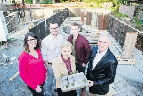  ?? GERRY KAHRMANN ?? John and Kathleen Higgins, front, display a model of four homes they’re building on a lot that used to hold their old 1970s-style rancher home. They’ll live in one home, son James (back, left) and wife Caitlin get No. 2, brother Patrick gets No. 3 and...