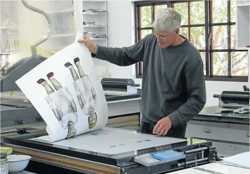  ??  ?? WIZARD AT WORK: Mark Attwood in his White River studio with a lithograph in progress, a print by Claudette Schreuders