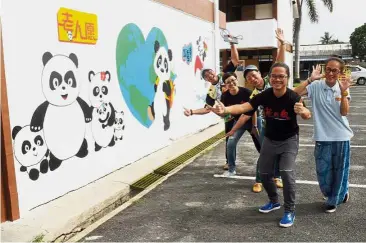  ??  ?? Joyous pandas: Lee (second right) and Tee (right) with ‘ Super Panda Team’ volunteers in front of a mural they painted at SJK(C) Long Chuan.