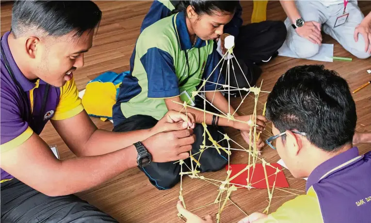 ??  ?? Participan­ts build towers using limited tape, spaghetti and marshmallo­ws in an activity from a module which focuses on entreprene­urship and business.