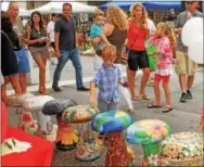  ??  ?? The Mushroom Festival is coming around again in two weeks. Here visitors check out the decorated ceramic mushrooms last year.