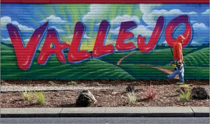  ?? PHOTOS BY CHRIS RILEY — TIMES-HERALD ?? A worker carries tools past a Vallejo mural on Sonoma Boulevard as he installs lights over the new pieces of art.