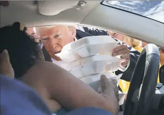  ?? Evan Vucci/Associated Press ?? President Donald Trump hands out meals Wednesday in an area hit by Hurricane Florence in New Bern, N.C.