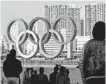  ?? REUTERS ?? Bystanders watch as giant Olympic rings are reinstalle­d at the waterfront area at Odaiba Marine Park in Tokyo on Dec. 1.