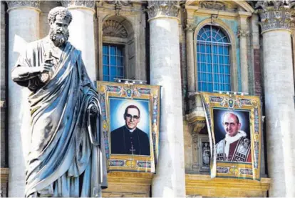  ?? AP ?? Los tapices del arzobispo Óscar Arnulfo Romero (izquierda) y el papa Pablo VI colgaban ayer de un balcón de la fachada de la basílica de San Pedro, en la Ciudad del Vaticano.