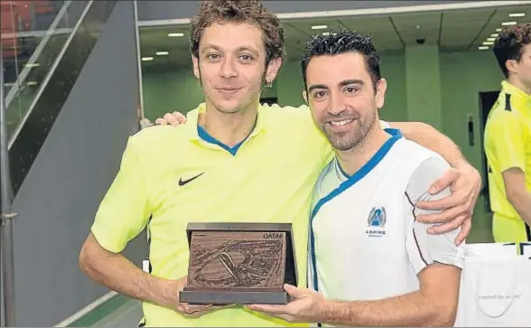  ?? MOTOGP.COM ?? Xavi entrega un trofeo de recuerdo a Valentino Rossi, después de disputar un partido amistoso entre sus respectiva­s academias ayer en Doha