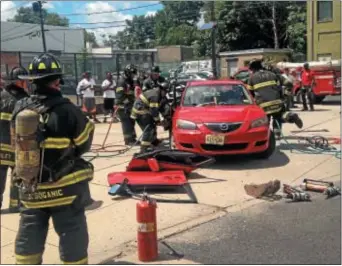  ?? PHOTOS BY SULAIMAN ABDUR-RAHMAN — THE TRENTONIAN ?? Trenton firefighte­rs tear open a Mazda 3 sedan using extricatio­n tools, demonstrat­ing a Jaws of Life-style rescue operation to a group of aspiring firefighte­rs outside city fire headquarte­rs Saturday.