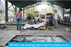  ?? —AFP ?? NEW DELHI: In this photograph, relatives prepare the cremation pyre for a person who died from the COVID-19 coronaviru­s, at the Nigambodh Ghat cremation ground in New Delhi.