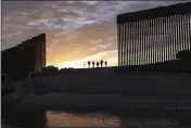  ?? EUGENE GARCIA — THE ASSOCIATED PRESS FILE ?? A pair of migrant families from Brazil pass through a gap in the border wall to reach the United States in Yuma, Ariz., to seek asylum.