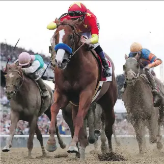  ?? ROB CARR/GETTY IMAGES ?? Justify, ridden by jockey Mike Smith, crosses the finish line to win the 150th running of the Belmont Stakes at Belmont Park Saturday in Elmont, N.Y. Justify became the 13th Triple Crown winner and the second in four years since American Pharoah broke...