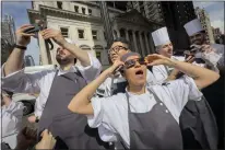  ?? JOHN MINCHILLO — THE ASSOCIATED PRESS ?? Restaurant workers in the Flatiron district of Manhattan take a break to view the solar eclipse,Monday in New York.