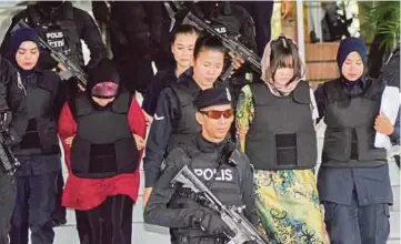  ??  ?? SITI Aisyah (belakang) dan Doan (depan) dikawal oleh anggota
polis ketika keluar dari Mahkamah Tinggi Shah Alam.