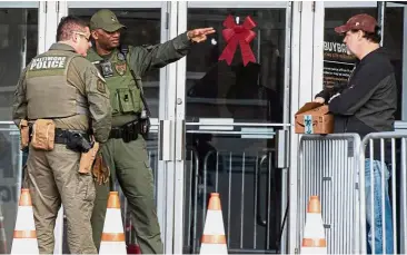  ?? — AFP ?? Here be guns: Baltimore policemen speaking with a man as he arrives at the Shake and Bake Community Center in Baltimore for the gun buy-back programme.