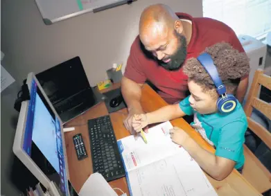  ?? CARLINE JEAN/SOUTH FLORIDA SUN SENTINEL ?? Miguel Reid, of Plantation, helps his son, James Reid, a first grader at Central Park Elementary with e-learning Friday. Florida schools are concluding that e-learning has been a failure, and it may be time for students to return to school.