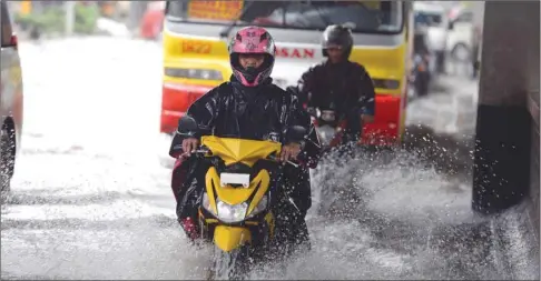  ??  ?? Motorists drive along a flooded street in Manila yesterday, as a tropical depression, locally named Henry, made landfall in northern Luzon island affecting suburban Manila and nearby provinces with monsoon rains.
