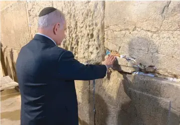  ??  ?? PRIME MINISTER Benjamin Netanyahu puts a note in the Western Wall yesterday. Right: Blue and White leader Benny Gantz poses for a selfie with supporters at his election campaign event in Kfar Ahim.