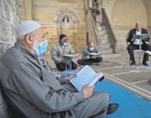  ??  ?? Muslim men read the Quran during Ramadan in Gaza city, Palestine, April 13, 2021.