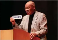  ?? AP FILE PHOTO BY JEREMY HOGAN ?? In this 2012 photo, Indiana University alumnus and former NFL player George Taliaferro holds the "COLORED" sign he took from the Princess Theater during the 1940s, when all the Bloomingto­n theaters were segregated, in Bloomingto­n, Ind.