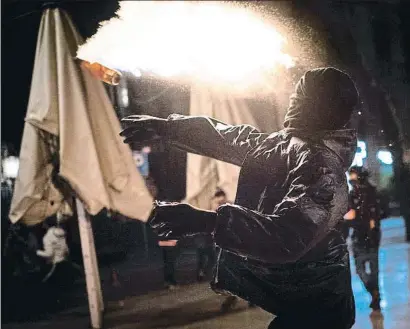  ?? EMILIO MORENATTI / AP ?? Un jove llançant un artefacte incendiari contra els vehicles policials estacionat­s a la Rambla dissabte