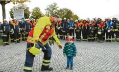  ??  ?? Kreisbrand­rat Stefan Kreitmeier begrüßte den jüngsten Zuschauer, den kleinen Noah, der später unbedingt Feuerwehrm­ann werden will.