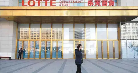  ??  ?? SHENYANG, China: This photo taken on March 1, 2017 shows a woman walking past a Lotte Department Store in northeast China’s Liaoning province. — AFP