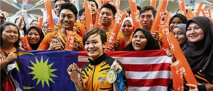  ?? — GLENN GUAN/ The Star ?? Fans sharing in Jun Hoong’s win when the diver arrived at KL Internatio­nal Airport. Hero’s welcome: