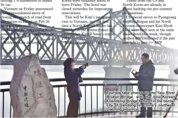  ??  ?? Tourists take photos on the Yalu River Broken Bridge, with the Sino-Korean Friendship Bridge behind, in the border city of Dandong, in China's northeast Liaoning province .