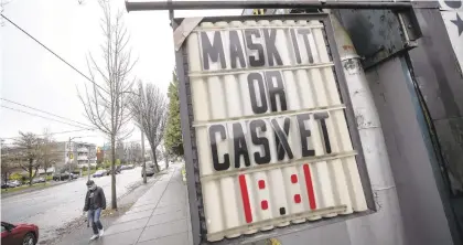  ?? DARRYLDYCK/AP ?? A sign regarding mask use hangs outside a business in Vancouver, British Columbia. Columnist Paul Muschick says if businesses are making good faith efforts to comply with virus-related restrictio­ns, there should be a high bar to sue them over any exposure.