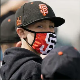  ?? JAE C. HONG — THE ASSOCIATED PRESS ?? A young baseball fan wears a face mask while watching Sunday’s spring game between the San Francisco Giants and the Los Angeles Angels in Scottsdale, Ariz. A limited number of spectators are being allowed to attend spring training contests this season.