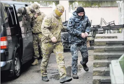  ??  ?? The Associated Press A Ukrainian sailor, right, is escorted by an officer of the FSB Russian intelligen­ce agency to a courtroom Tuesday in Simferopol, Crimea, where the crews of three Ukrainian ships seized by Russia were scheduled to have a court hearing.