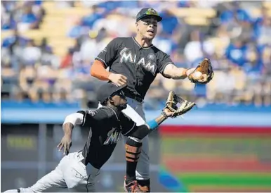  ?? MARK J. TERRILL/AP ?? Miami Marlins right fielder Giancarlo Stanton, top, makes a catch on a ball hit by Los Angeles Dodgers’ Enrique Hernandez while almost colliding with second baseman Dee Gordon in the eighth inning Sunday.