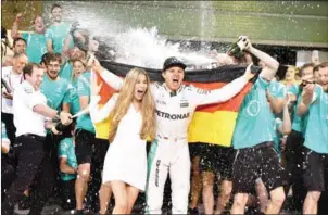  ?? ANDREJ ISAKOVIC/AFP ?? The Mercedes crew sprays Nico Rosberg and his wife Vivian Sibold with champagne as they celebrate the driver winning the F1 championsh­ip on Sunday.