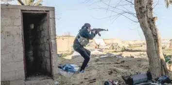  ?? — AFP ?? A fighter with the Syrian Democratic Forces takes aim with his Kalashniko­v assault rifle after seeing a man walking towards his position in Baghouz, in the eastern Syrian province of Deir Ezzor, on Saturday.